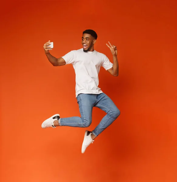 Happy man jumping and taking selfie on smartphone — Stock Photo, Image