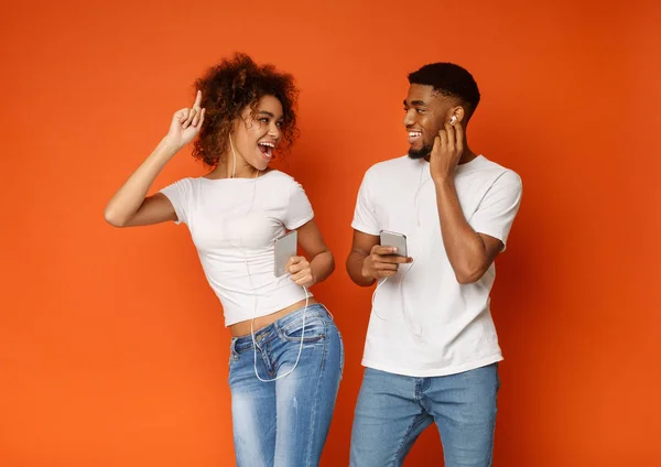 Pria dan wanita dengan earphone hitam mendengarkan musik di ponsel — Stok Foto