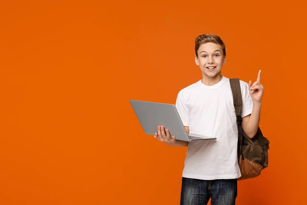 Веселый мальчик с ноутбуком удивлен идеей показывать пальцем вверх — стоковое фото