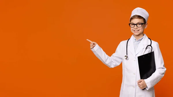 Söta leende pojke spelar läkare på orange bakgrund — Stockfoto