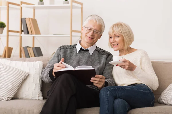 Seniorenpaar liest Buch auf Couch zu Hause — Stockfoto