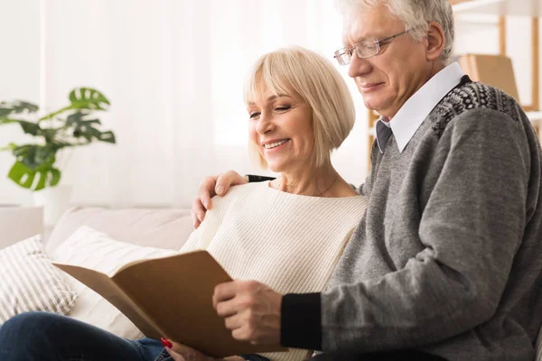 Feliz pareja de ancianos mirando álbum de fotos juntos —  Fotos de Stock