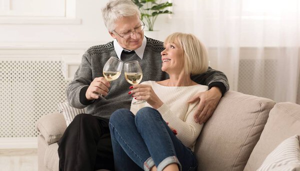 Happy senior couple clinking glasses of white wine