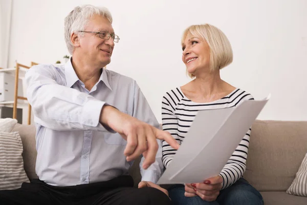 Älteres Paar diskutiert Dokumente, schaut sich einander an — Stockfoto