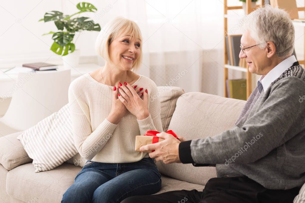 Senior man giving present to wife, celebrating anniversary