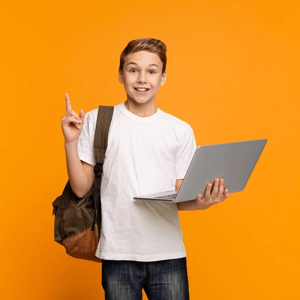 Menino alegre segurando laptop surpreso com ideia apontando dedo para cima — Fotografia de Stock