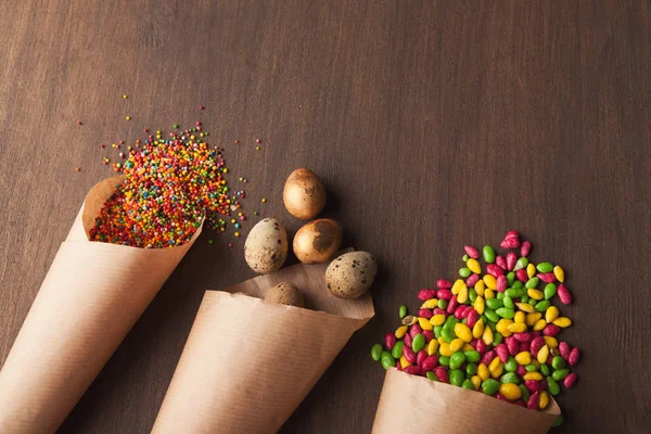 Яйца и цветные конфеты в бумажных корнетах — стоковое фото