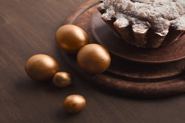 Золотые яйца и пасхальный торт на столе — стоковое фото