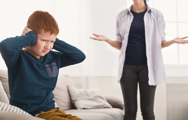 Расстроенный мальчик закрывает уши, когда мать ругает его — стоковое фото
