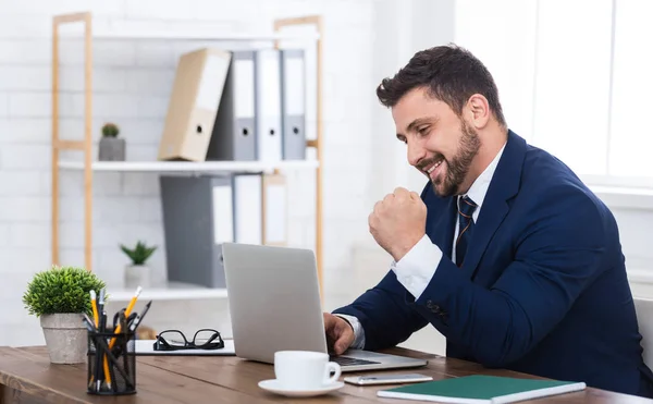 Glad affärsman med laptop, firar framgångar i office — Stockfoto