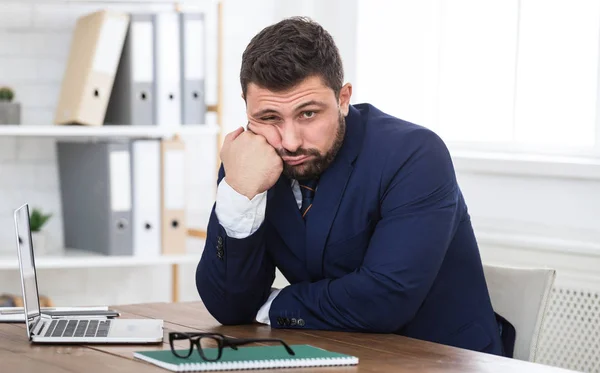 Joven empresario cansado sentado en el lugar de trabajo en la oficina — Foto de Stock