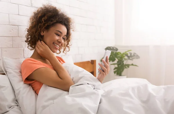 Woman talking on video call, lying in bed