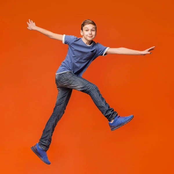 Liten pojke hoppar på orange studio bakgrund — Stockfoto