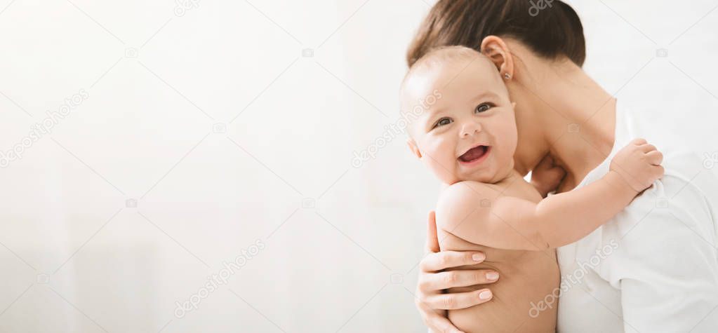 Adorable laughing baby on mothers hands copy space