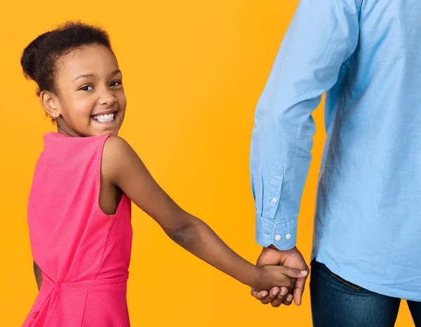 Afroamerikansk flicka håller fäder hand och tittar på kameran — Stockfoto