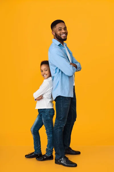 African-american father and daughter standing back to back