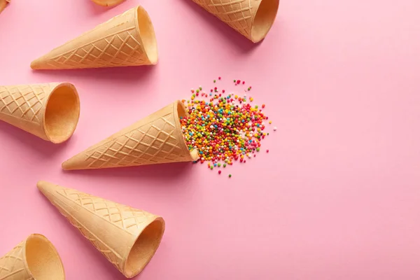 Conos de gofre de helado vacíos y salpicaduras de colores sobre fondo rosa , — Foto de Stock