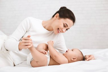 Yatak odasında bebeği ile oynarken annesi.