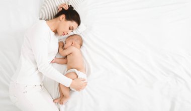 Genç Anne ve yatakta uyuyan sevimli bebek