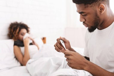 Hasta bir kadın yatakta, termometre sıcaklık kontrol adam