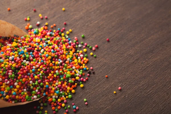 Polvilhas doces coloridas no fundo de madeira — Fotografia de Stock