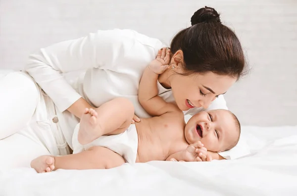 Csiklandozás a baba játék az ágyban otthon anya — Stock Fotó