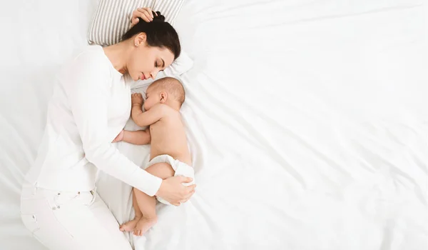 年轻的妈妈和她可爱的宝宝睡在床上 — 图库照片