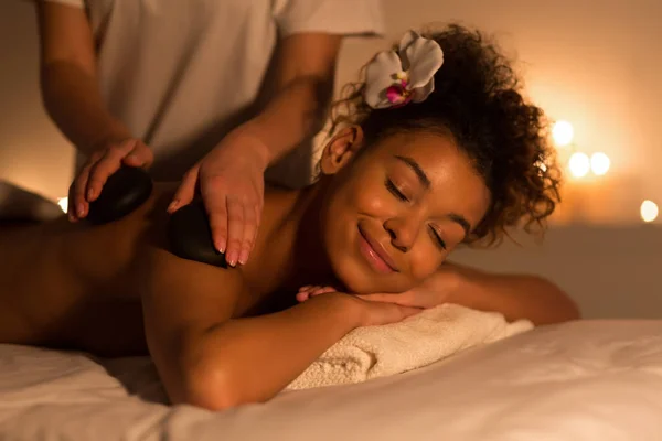 Afroamerikansk kvinna att få stenar arm massage i spa — Stockfoto