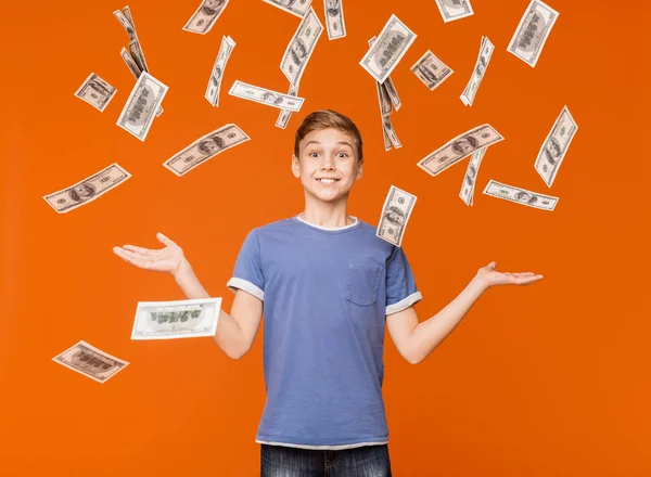 Menino gostando de dinheiro chuva no fundo laranja — Fotografia de Stock