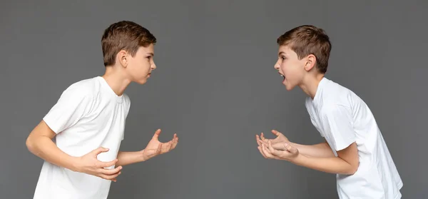Twin brothers having quarrel with each other over studio background — Stock Photo, Image