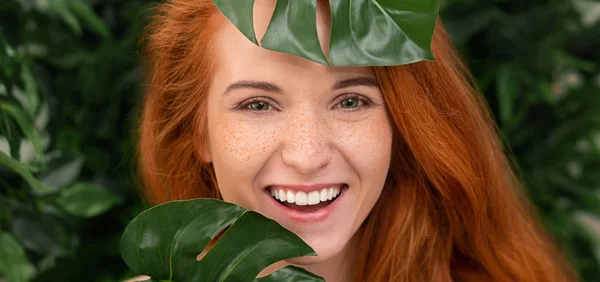 Monstera yaprakları gülüyor neşeli Kızıl saçlı kadın — Stok fotoğraf