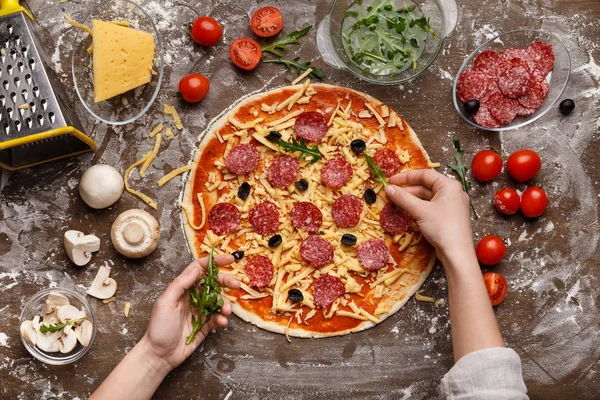 Koch ergänzt Pizza mit Rucola, Draufsicht — Stockfoto