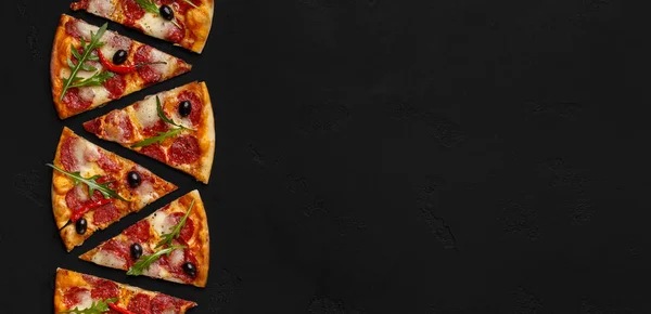 Rebanadas de pizza con salami y ensalada de rúcula sobre fondo negro — Foto de Stock