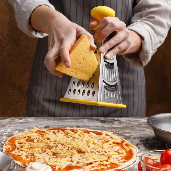 Σεφ στην κουζίνα το ψέκασμα πίτσα με τυρί — Φωτογραφία Αρχείου