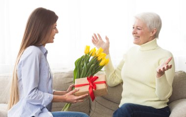 Kadın, olgun annesine lale ve hediye kutusu veriyor.