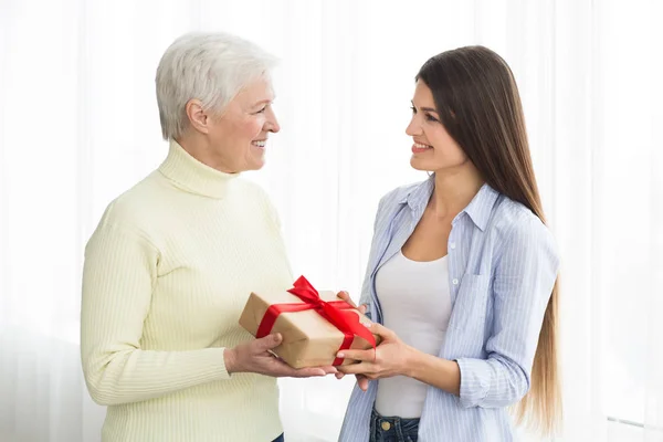 Senior woman receiving gift from adult daughter — Stock Photo, Image