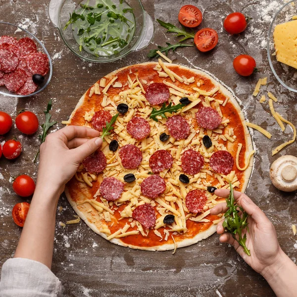 Koch dekoriert Pizza mit Rucola, Draufsicht — Stockfoto