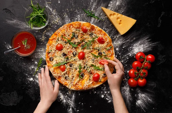 Koch bereitet Pizza zu und dekoriert sie mit Kirschtomaten — Stockfoto