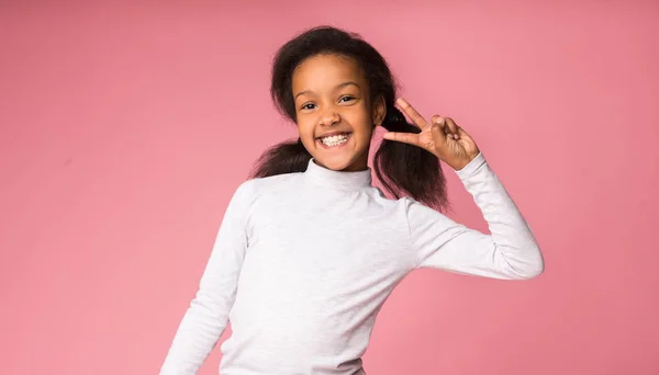 Muchacha divertida mostrando signo de victoria, fondo rosa — Foto de Stock