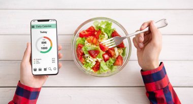 Smartphone kullanarak ve taze salata yemek erkek eller