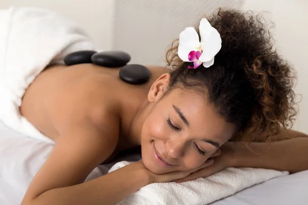 Kvinna som njuter av hot stone-massage på spasalong — Stockfoto