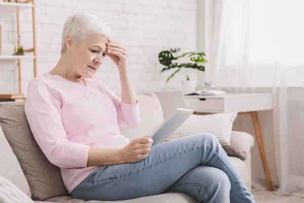 Mulher idosa confusa usando tablet em casa — Fotografia de Stock