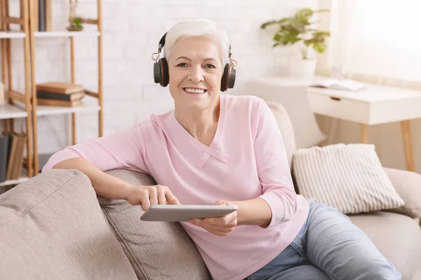 Mujer mayor disfrutando de la música y viendo videos en la tableta PC — Foto de Stock