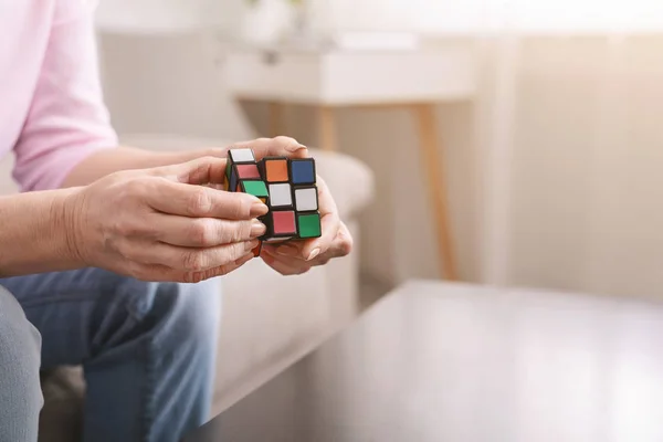 Oude vrouw houden van Rubiks kubus en spelen met het — Stockfoto