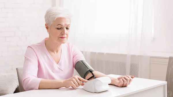 Mujer mayor midiendo su presión arterial en casa. —  Fotos de Stock