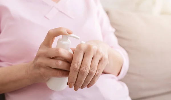 Mains femme âgée avec crème hydratante gros plan — Photo