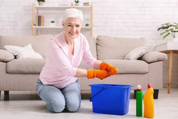Uśmiechający się starsza gospodyni czyszczenia podłogi w domu — Zdjęcie stockowe