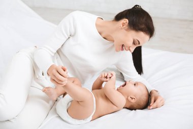 Yatak odasında bebeği ile oynarken annesi.