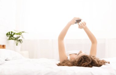 Bin yıllık kadın yatakta cep telefonu üzerinde ağ