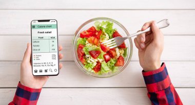 Smartphone kullanarak ve taze salata yemek erkek eller